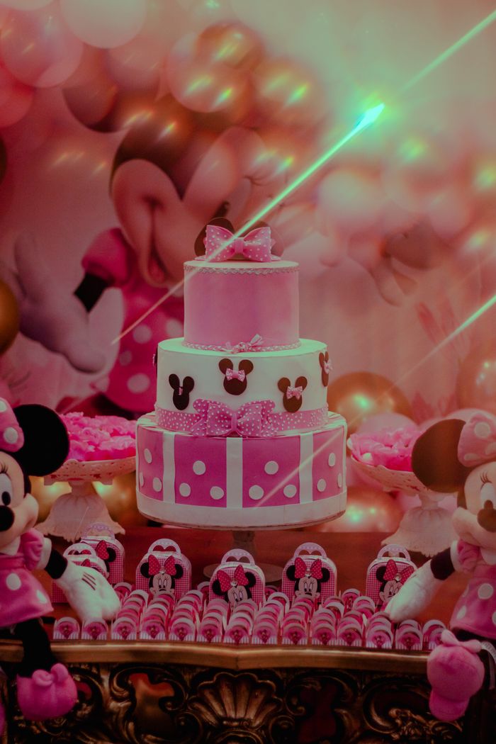 Colorful Minnie Mouse themed birthday setup with a pink cake and decorations.